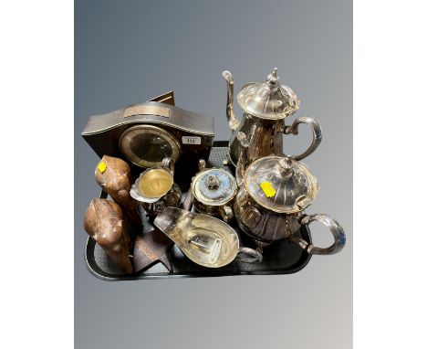 A tray containing a mid-20th century mantel clock, a four-piece plated tea service, carved hardwood elephants.