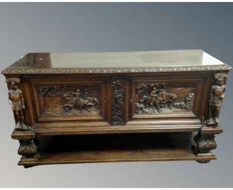 An early 20th century heavily carved oak double door sideboard fitted with shelf beneath.