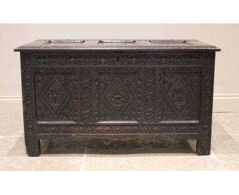 A late 17th century/early 18th century carved oak coffer, the three panel cover opening to a fitted candle box, above a friez