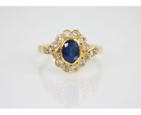 A sapphire and diamond 18ct gold cluster ring, the central oval mixed cut sapphire measuring 6.5mm x 4.75mm, with a diamond s