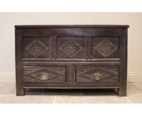 An 18th century carved oak mule chest, the four panel hinged top over three front panels and two drawers, all carved with loz