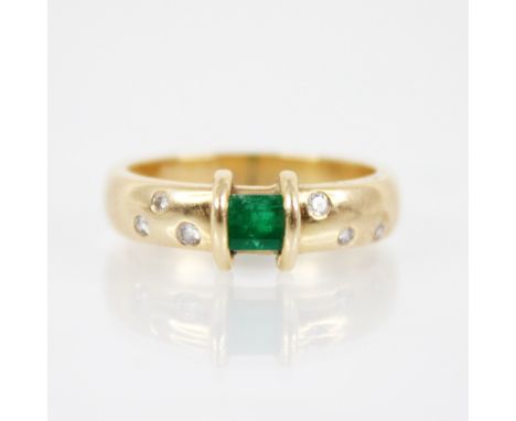 An emerald and diamond ring, the central rectangular step cut emerald measuring 3.8mm x 4.8mm, to an arched rubover setting, 
