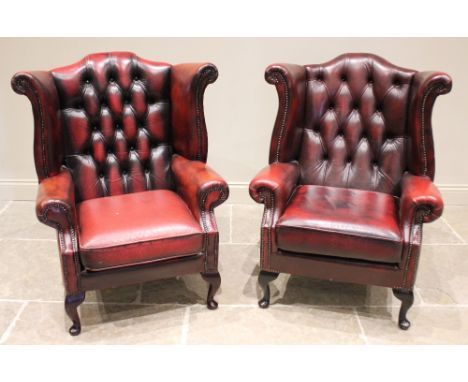 A pair of George III style ox-blood red leather wing back armchairs, late 20th century, each with an arched button back exten