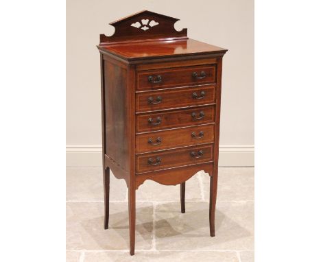 An Edwardian mahogany and rosewood crossbanded music cabinet, the pierced architectural pediment above the rectangular top an