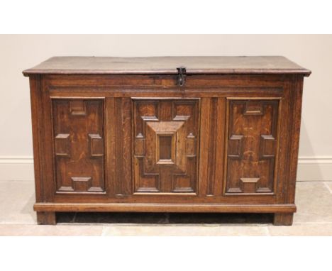 A late 17th/early 18th century oak coffer, the twin plank moulded top opening to a fitted candle box above a frieze centred w