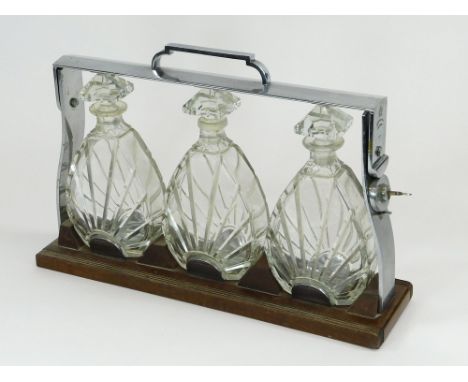 BETJEMANN'S TANTALUS. An Art Deco Betjemann's Patent tantalus. The walnut & chromium frame holding three cut glass decanters.