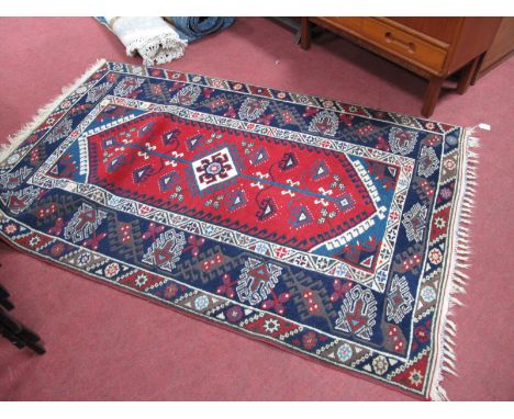 Middle Eastern Wool Tasseled Rug with geometric decorative central panel on red ground. Floral and other motifs to blue borde