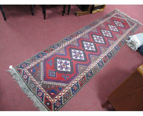 A Middle Eastern Wool Tassled Runner, with seven large geometric lozenges on red ground within floral boarder 282 x 76cm