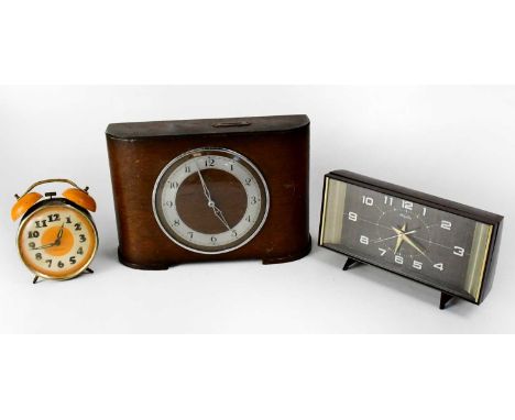 Three mid-20th century clocks comprising a Rhythm alarm clock in brown plastic case, a 1930s oak cased mantel clock and a Wes