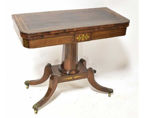 A Regency brass-inlaid rosewood fold-over card table, raised on octagonal tapering column to brass inlaid quadripartite base,