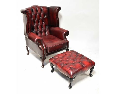 A contemporary Chesterfield-style oxblood leather button pressed wing-back armchair, raised on cabriole front supports, with 