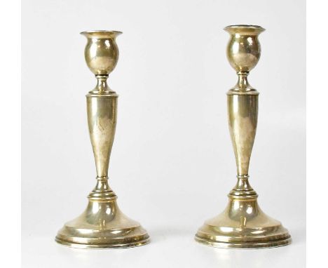 EDWARD BARNARD &amp; SONS LTD; a pair of Edward VII hallmarked silver Neoclassical candlesticks with tapered stems, on domed 