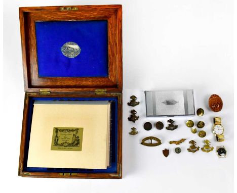 A collectors' lot comprising military cap badges, stainless steel cigarette case, reproduction engravings of London scenes, a
