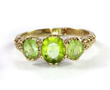 A 9ct yellow gold ring set with three oval cut peridots, (Q.5).