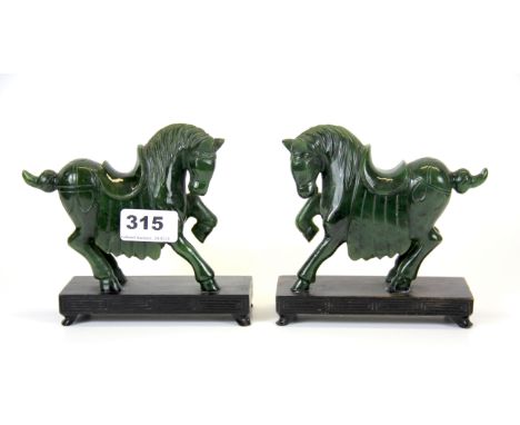 A pair of Chinese carved deep green jade horses on carved wooden plinths, H. 13cm.