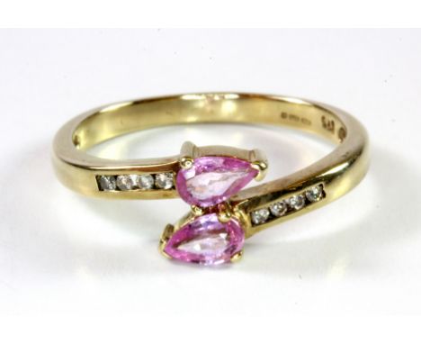 A 9ct yellow gold crossover ring set with pear cut pink sapphires and diamond set shoulders, (N).