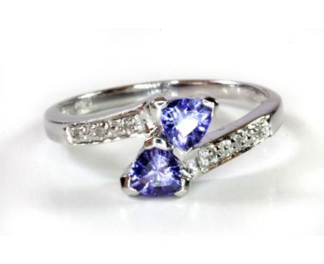 A 9ct white gold tanzanite and diamond set crossover ring, (L.5).