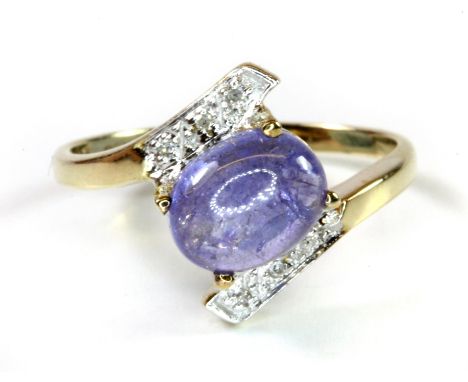 A 9ct yellow gold crossover ring set with a cabochon cut tanzanite and diamonds, (L.5).