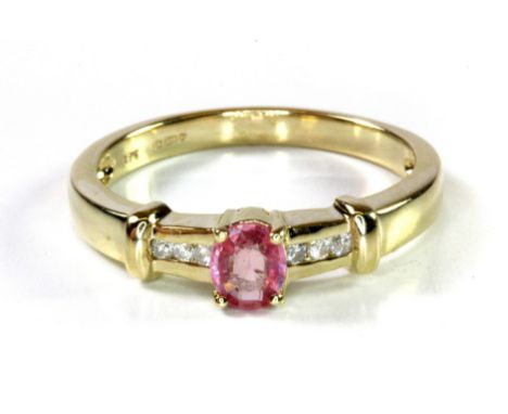 A 9ct yellow gold ring set with an oval cut pink sapphire and diamond set shoulders, (N).