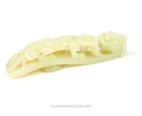 A Chinese translucent jadeite jade belt hook, of typical form, carved with a dragons head and a baby dragon on his back, 10.5