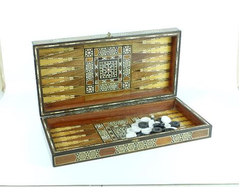 An eastern inlaid folding chess / backgammon board, with an associated set of draughts pieces, 8 x 49 x 24.5cm when closed.