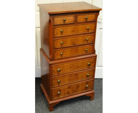A reproduction yew chest on chest holding two short above three long drawers, stepped base holding a further three drawers, b
