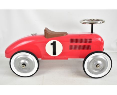 A contemporary child's ride-on tin plate racing car with red and white painted body, plastic seat and working steering wheel 