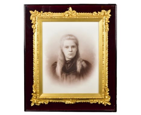 A late 19th/early 20th century gilt photograph frame with applied foliate decoration and further moulded detail, with sepia p