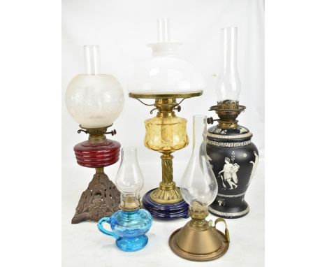 Five late 19th/early 20th century oil lamps of varied size and form, the largest with opaque white shade above yellow glass r