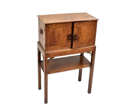 An early 20th century Arts &amp; Crafts oak smoker's cabinet, the twin hinged doors enclosing part fitted interior including 