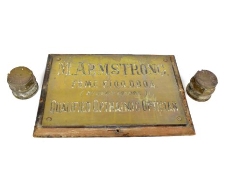 An original brass advertising sign 'M. Armstrong F.S.M.C, F.I.O.O.D. B.O.A (By Exam London) Qualified Ophthalmic Optician', w