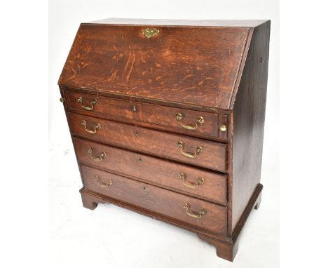 A Georgian oak bureau, the fall-front enclosing a fitted interior with green leather slope, above one short and three long dr