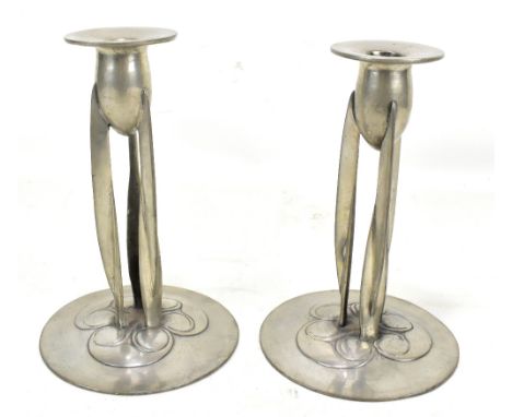 ARCHIBALD KNOX FOR TUDRIC PEWTER AND LIBERTY &amp; CO; a pair of Arts and Crafts candlesticks, the circular sconce raised on 