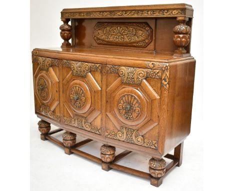 An early 20th century carved oak sideboard, the back with central carved panel flanked by carved pineapples above three bow f