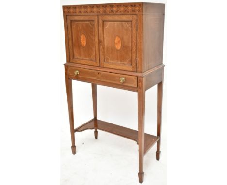 An Edwardian Arts &amp; Crafts mahogany, burr walnut and further inlaid cabinet, the upper section with twin doors enclosing 