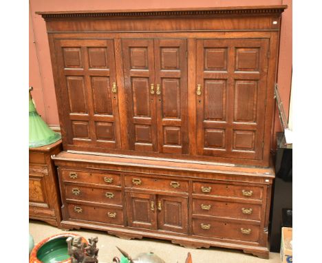 An 18th century oak housekeeper's cupboard, the upper section with four panelled doors enclosing an arrangement of shelves an