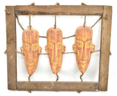 A set of three African painted ceramic stylised busts suspended on rope and housed in wooden frame, frame 46 x 55cm.Additiona