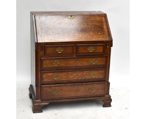 An oak and mahogany cross banded bureau, the fall front enclosing fitted interior, above two short and three long drawers on 
