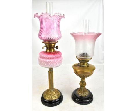 A Victorian oil lamp with a later cranberry glass shade and milk and cranberry glass reservoir, raised on brass Corinthian co