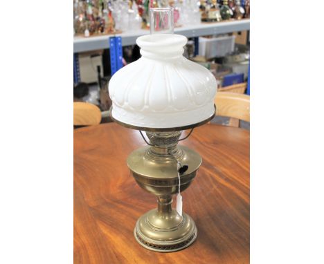 An antique brass oil lamp with glass chimney and shade