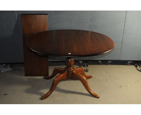 A modern Ercol dining table, in light brown wood, possibly oak, circular with extension leaf on pedastal base (2)