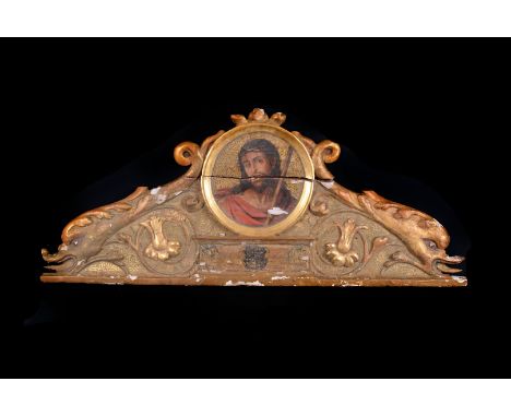 An early 19th century religios carving, the carved frieze with oval panel with painted image of Christ, flanked by gilt paint