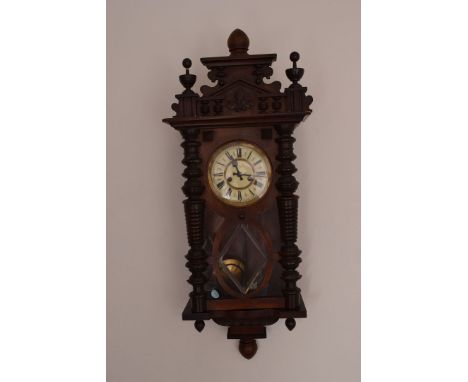 A Vienna style wall clock, having black Roman numerals, behind a glazed front, flanked by column design 