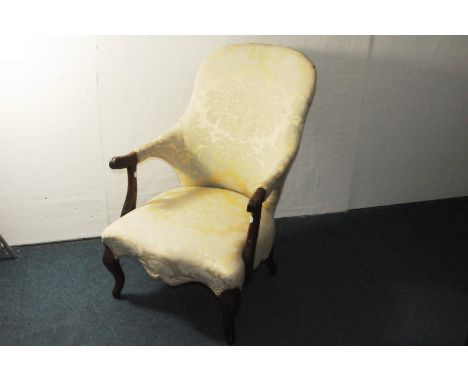 A Victorian walnut armchair, with carved frame and light yelllow upholstery