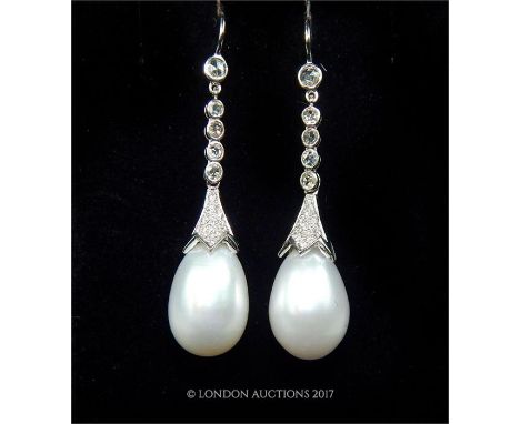 A pair of 18 ct white gold diamond and pearl drop earrings, each white pearl is attached to a truncated pave diamond mount an