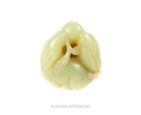 A Chinese jade carving depicting three dogs encircled, holding a branch with fruit in their mouths, 4 x4.5 x 4.5cm.