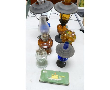 A collection of vintage oil lamps o include blue glass, amber glass together with a box of night lights. Height of tallest 40