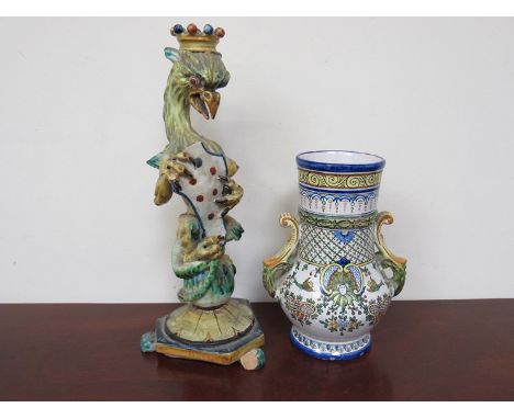 A Continental faience pottery jug and a pottery candlestick in the form of a crowned griffin holding a shield, seated on a ba