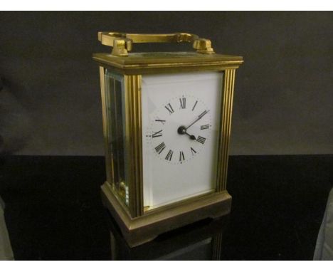 An early 20th Century brass carriage clock with enamelled Roman dial