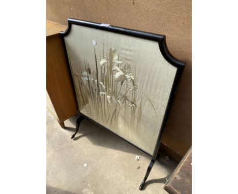 AN EARLY 20TH CENTURY FIRE SCREEN WITH BLACK FRAME AND SILK WORK PANEL DEPICTING FLOWERS